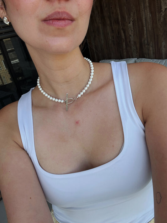 a selfie of a woman with a pearls chocker with a silver t clasp
