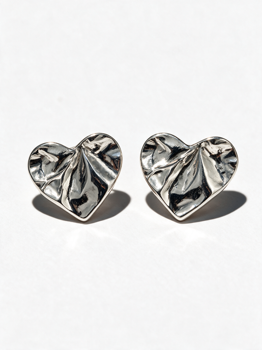 A pair of silver heart-shaped stud earrings with a textured, crinkled leaf-like surface, displayed on a clean white background with soft shadows.