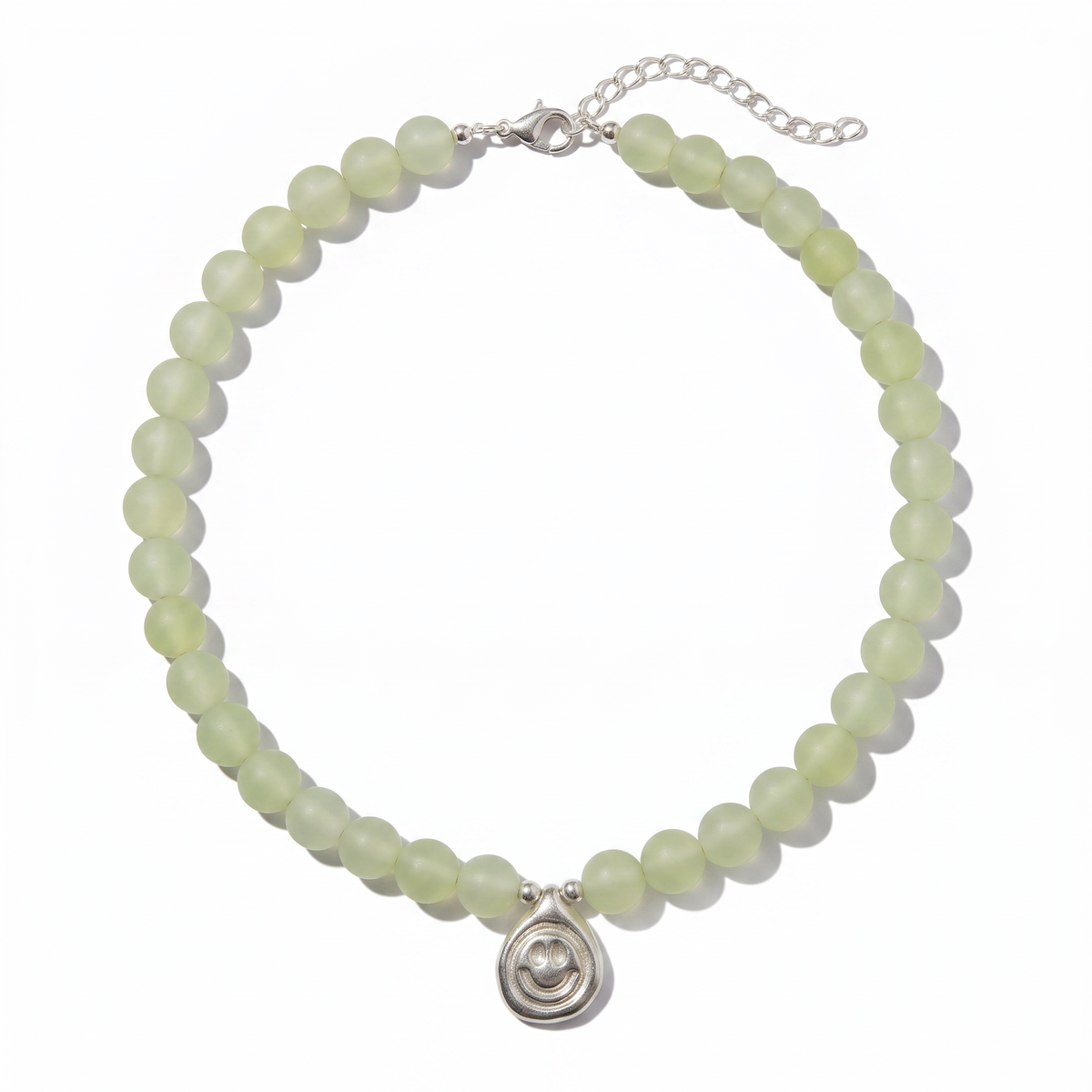 A beaded necklace made of pale green faceted beads with a silver-toned smiley charm, displayed on a clean white background.